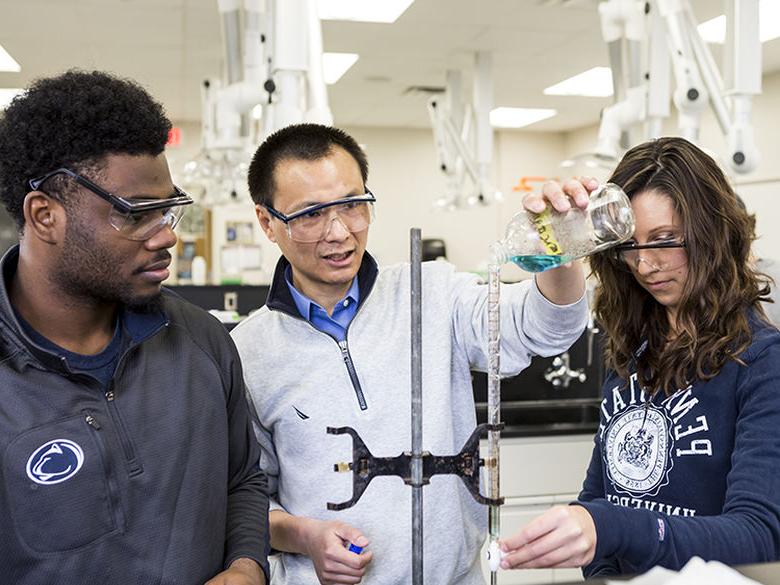 A female and a male student work in the chemistry lab with their instructor